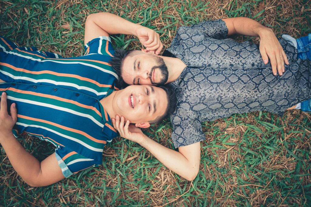 A happy couple enjoys a relaxing moment lying on grass outdoors in summer.