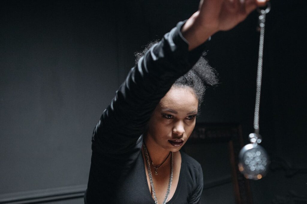 A woman performs a mystical ritual with a pendant in an atmospheric setting, capturing spiritual essence.